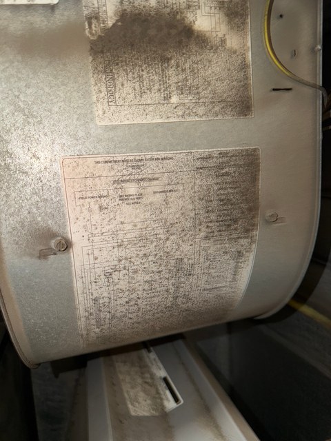 Dark speckled deposits across a blower housing and its factory labels