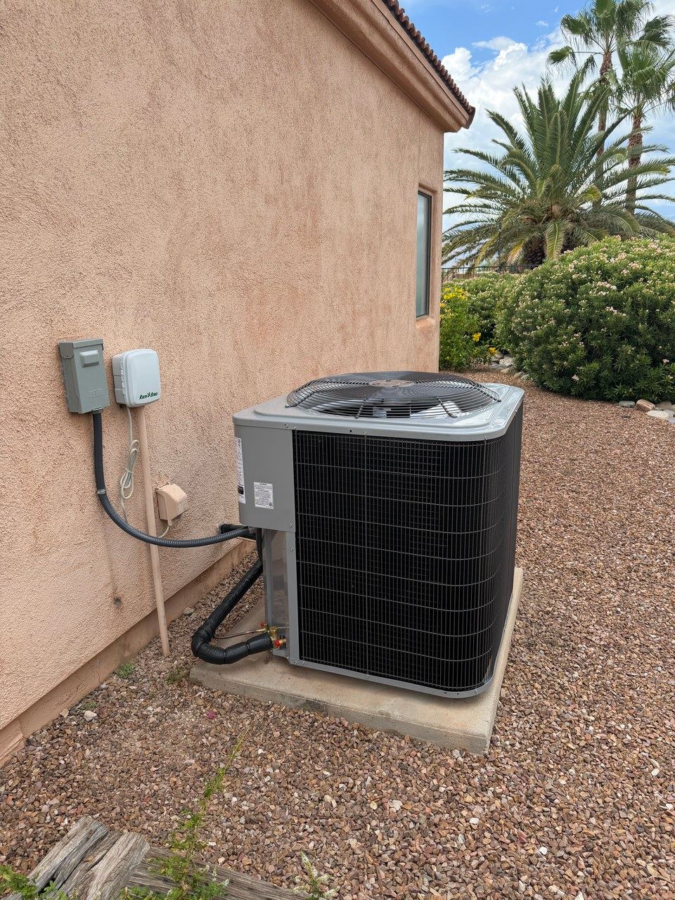 Outdoor condenser on a pad beside a stucco wall with insulated lines and conduit