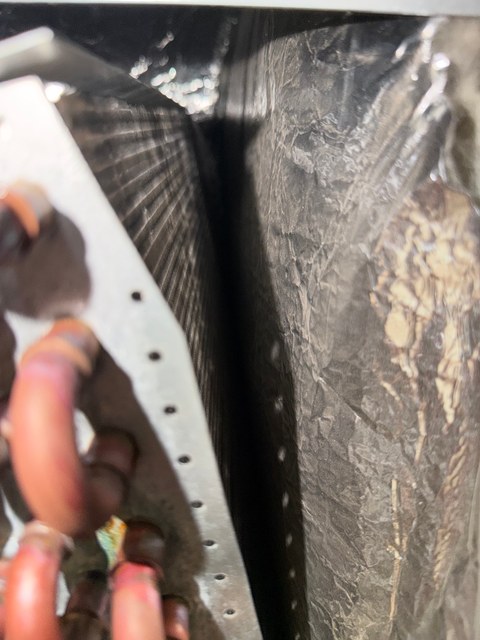 Indoor coil with a dense gray mat of debris obscuring one fin surface