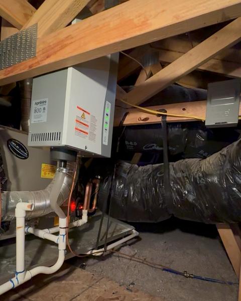 AprilAire Model 800 steam humidifier mounted in an attic, with steam hose and white condensate piping